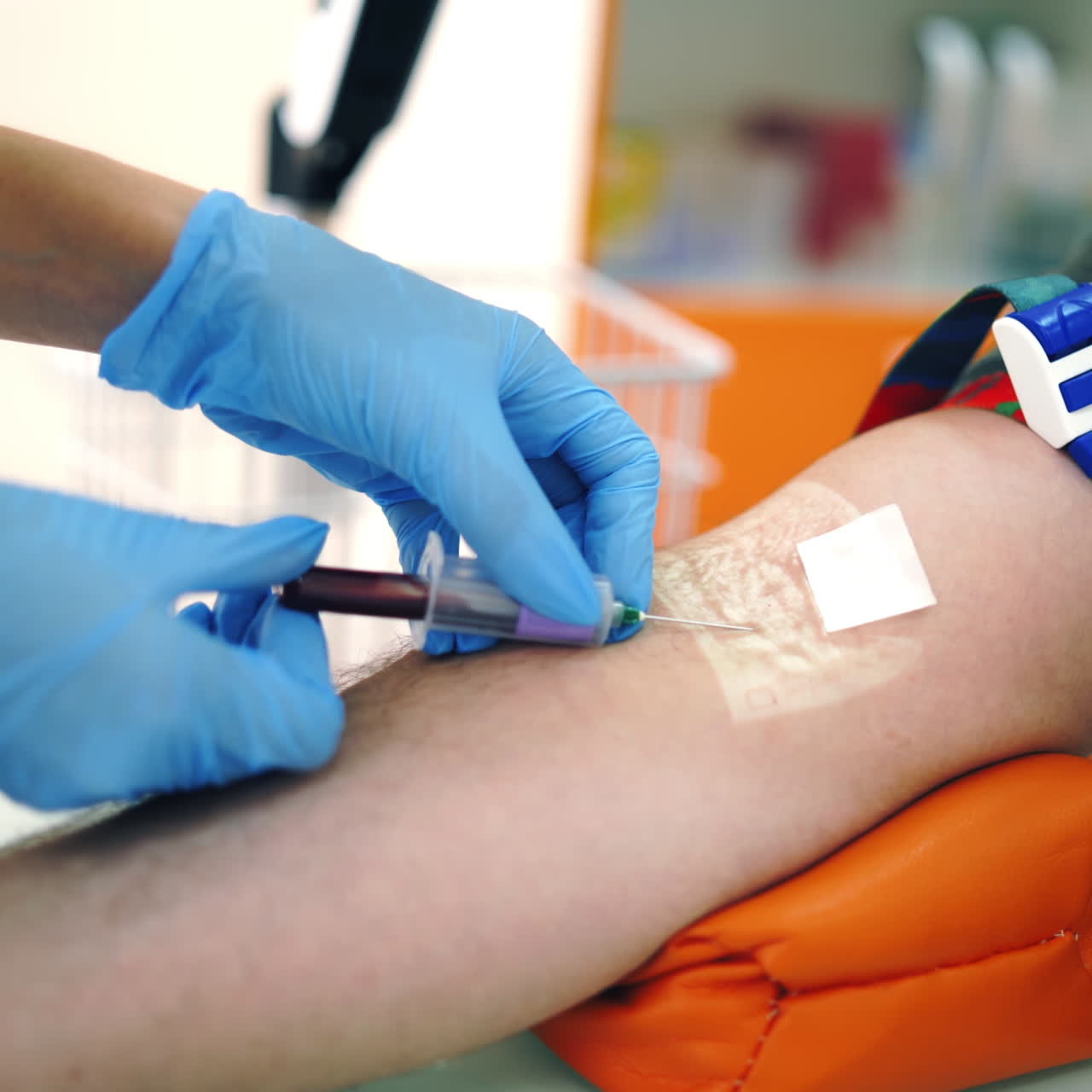Nurse taking blood sample from vein. Close-up worker's hands in sterile gloves collecting blood with syringe into vial from patient's arm. Healthcare concept.