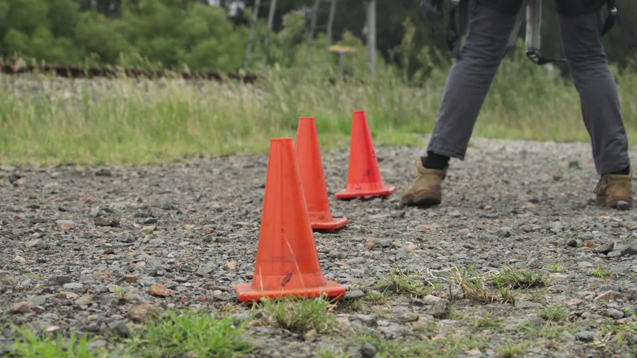 Close-up of bright orange safety cones placed on a gravel pathway to mark out a designated drop zone