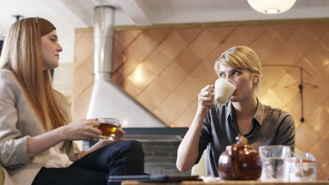 Zwei-Frauen-Nutzen-Ein-Digitales-Tablet-Und-Trinken-Kaffee-Im-Café