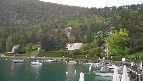 Boats-and-lake-shore-homes-at-village-of-Annecy-in-the-French-Alps,-Stable-wide-shot