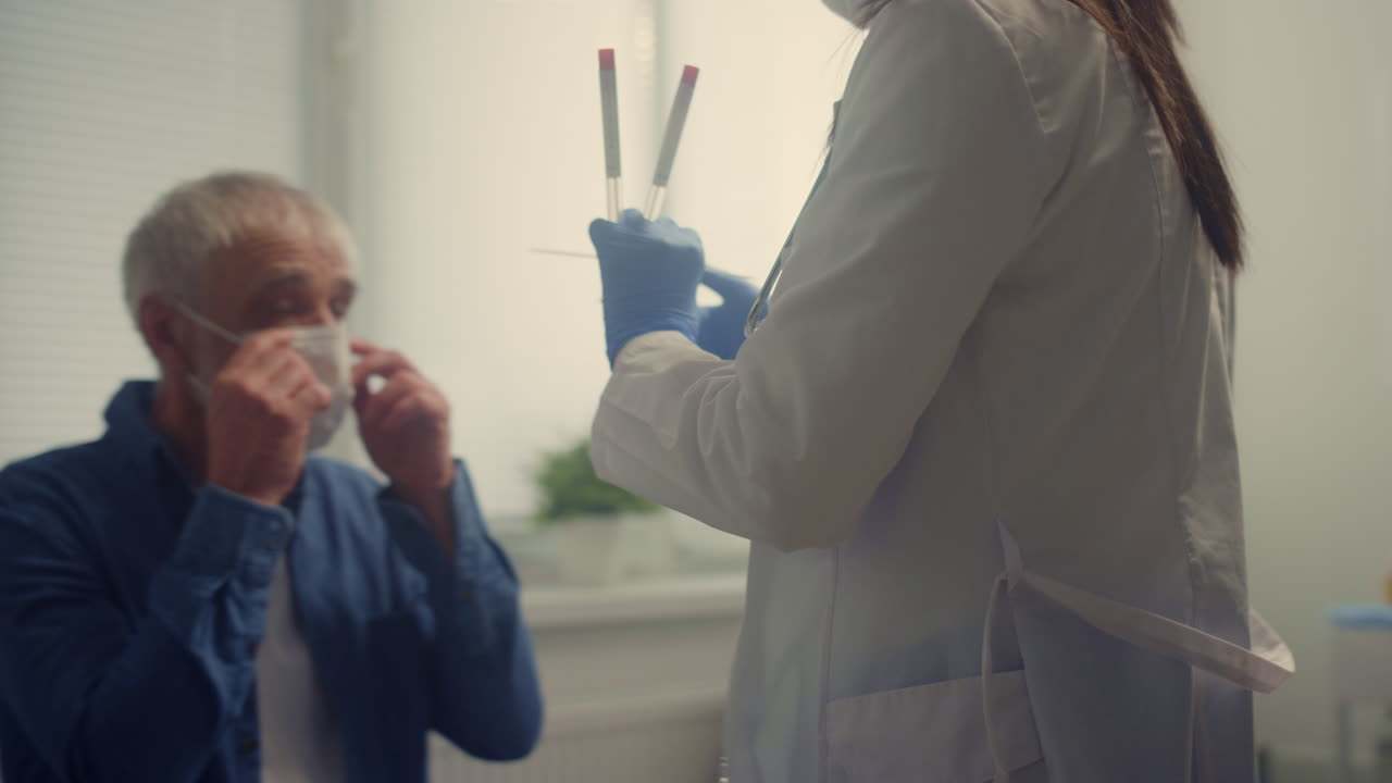 Woman medic taking saliva sample old patient. Doctor testing senior man on covid