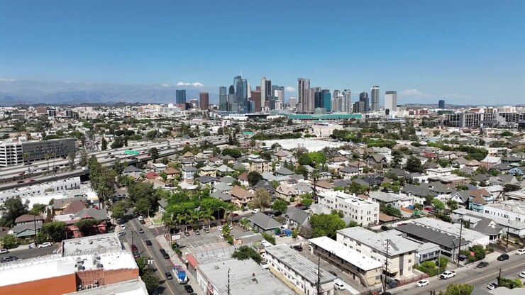 Le riprese aeree con drone rivelano lo skyline del centro di Los Angeles con alti edifici commerciali che si ergono sopra i quartieri residenziali circostanti pieni di case.