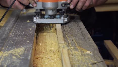 primer plano de una pieza de trabajo de carpintero masculino profesional de madera con una máquina enrutadora en un banco de trabajo