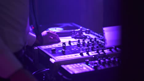 disc jockey dancing wearing a suit while mixing in music board