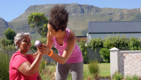 mixed-race personal trainer assisting asian senior woman in exercising at backyard of their home 4k