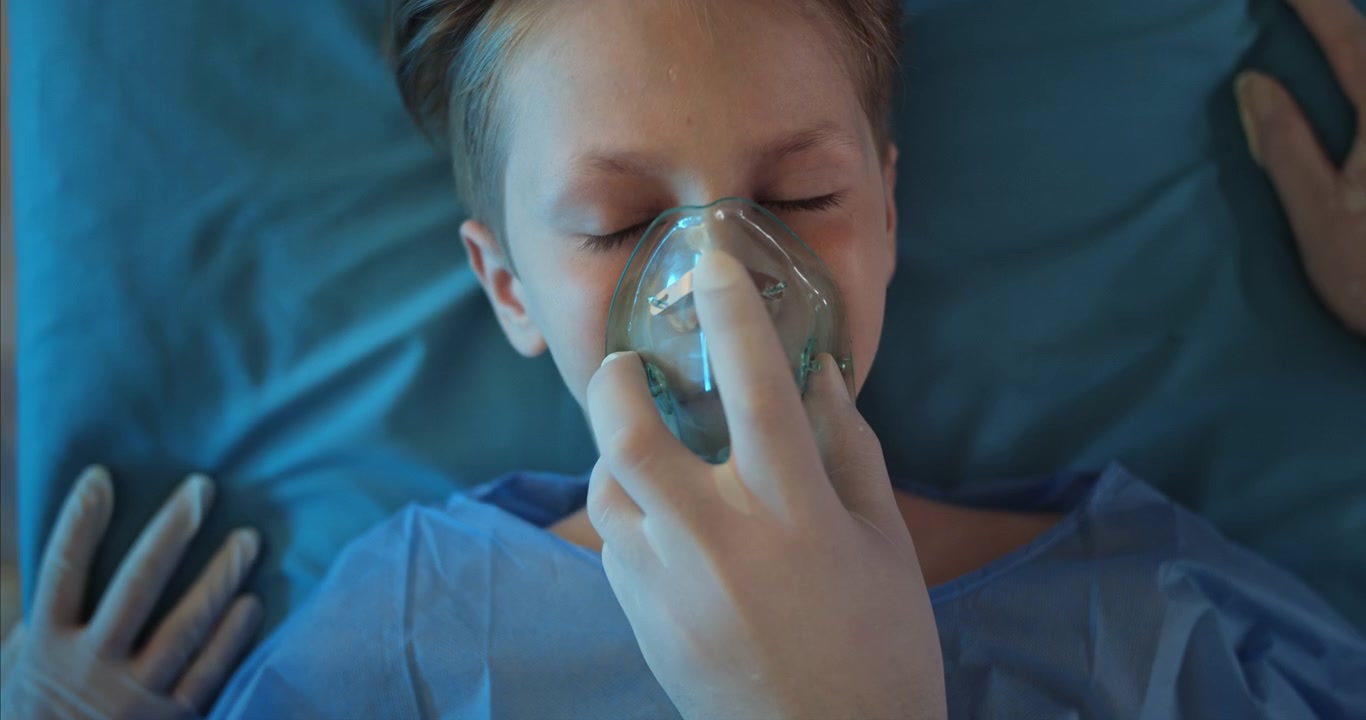 Personale medico che somministra una maschera per l'ossigeno a un giovane paziente bambino.
