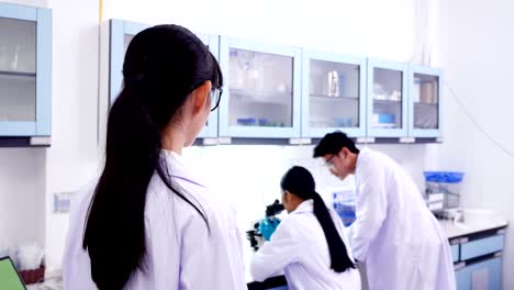 team of research scientists working in research lab. young female research scientist looking with attractive smiling. 4k resolution.