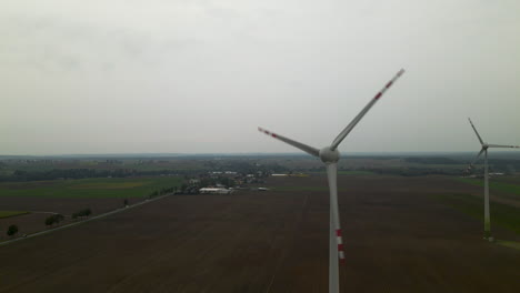 Dos-Molinos-De-Viento-De-Granja-Gigantes-Girando-En-El-Viento-Bajo-Un-Cielo-Sombrío-En-Polonia---Disparo-De-Drones