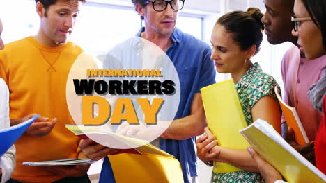 animation of international workers day over diverse female and male coworkers talking in office