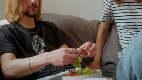 a man and a woman are playfully fighting over a bunch of grapes - close up