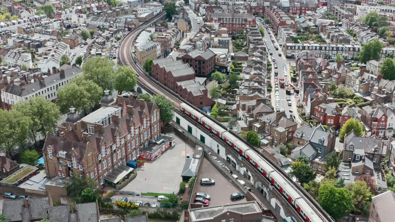 dron cinemático sigue la toma del tren de la línea del distrito que serpentea a través del puente residencial de londres putney