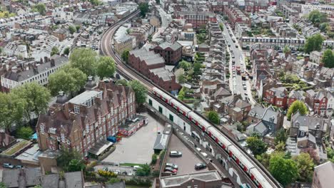 cinematic drone follow shot of district line train winding through residential london putney bridge