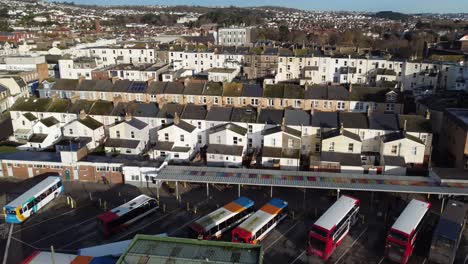 A-rising-shot-of-a-bus-station,-revealing-a-small-city-behind-in-the-distance