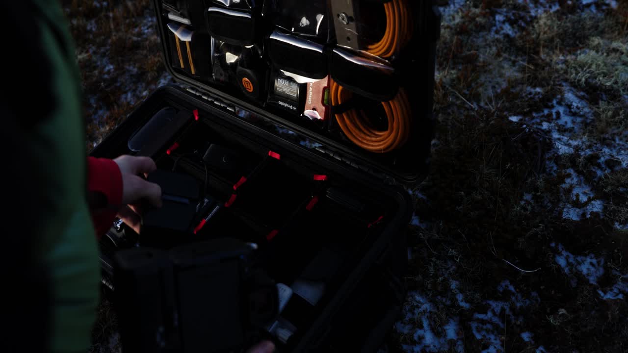 Man taking out large tele lens to put on camera from hard flight case, close up