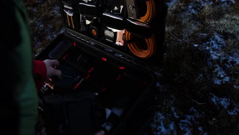 man taking out large tele lens to put on camera from hard flight case, close up