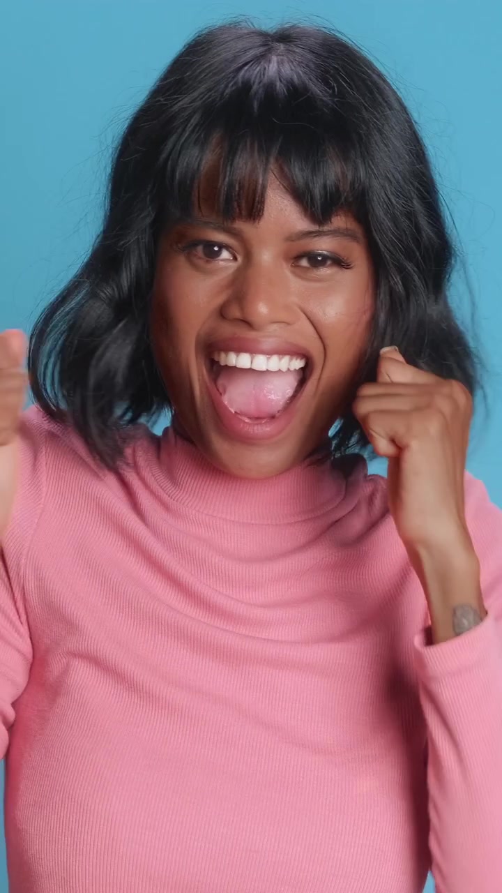 Happy asian woman with short black hair dancing and swaying on blue background