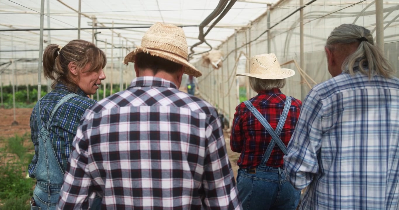 Group of Farmers Walking and Talking in a Greenhouse