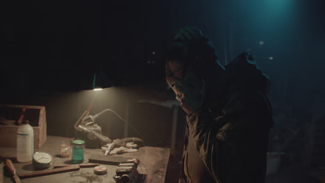 a bombmaker assembles a bomb in his workshop at night