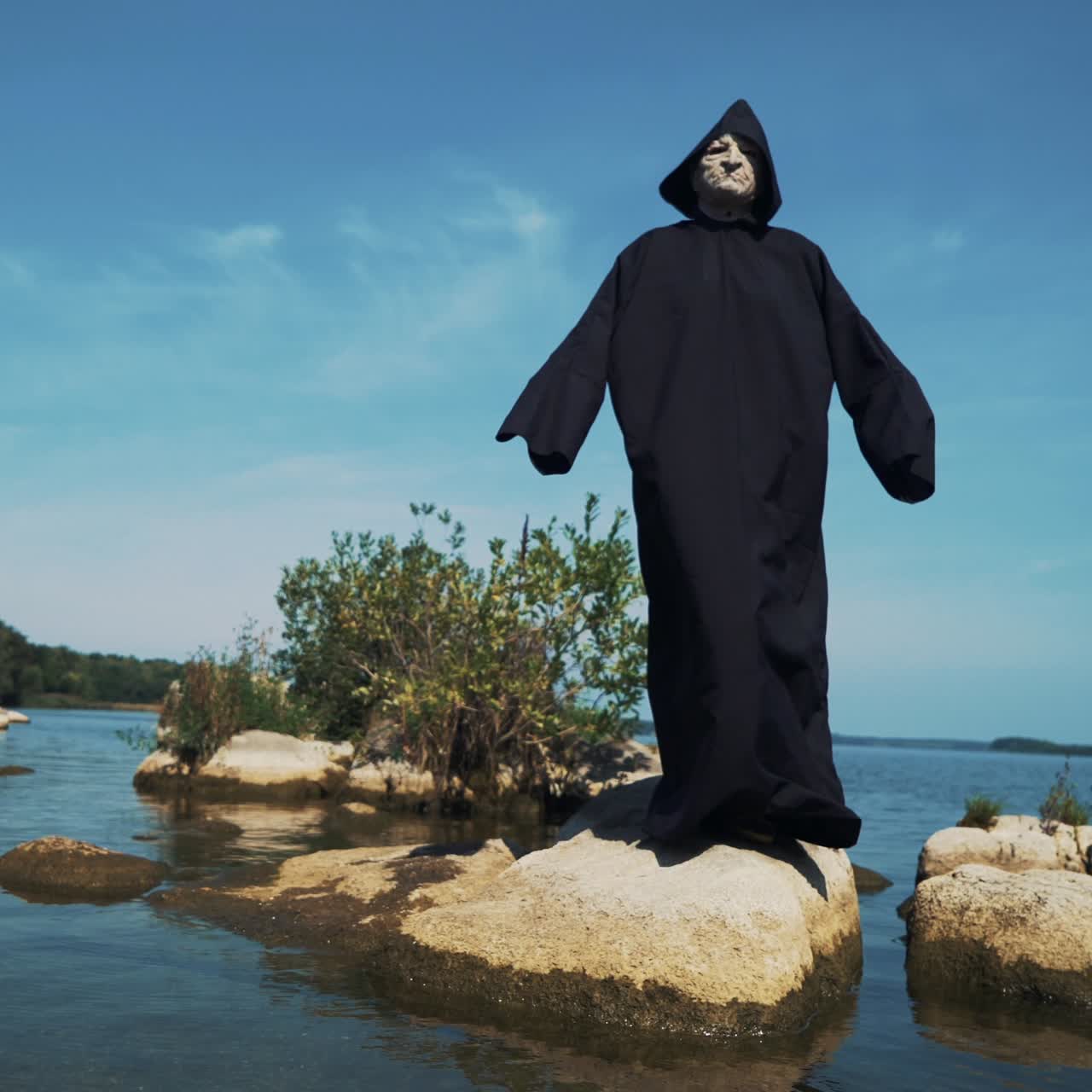 Eerie witch on river bank watches the camera