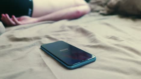 4k cinematic footage of a phone on a bed with the alarm going off and a man waking up to turn it off