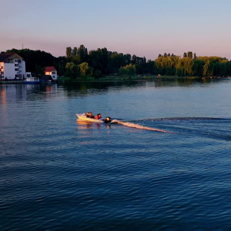people in motor boat at sunset. boats floating along the river on the background of power station in nature. beautiful orange sunlight over the river. aerial view.