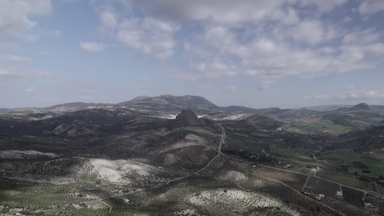 Aerial 4K footage of Olvera, Spain, captured with a DJI drone at 30fps. A cinematic view of open meadows with a stunning castle atop the mountain in the background.