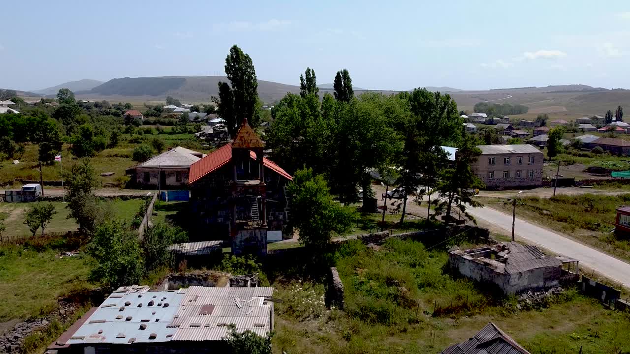 Discover the remnants of an abandoned village in Armenia featuring historic architecture, greenery, and a tranquil road set under a clear blue sky. Enjoy the serene landscapes