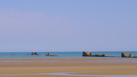 pan across historic gold beach d-day ww2 landing bay with artifical harbour ruins in sea in normandy, france, europe 4k