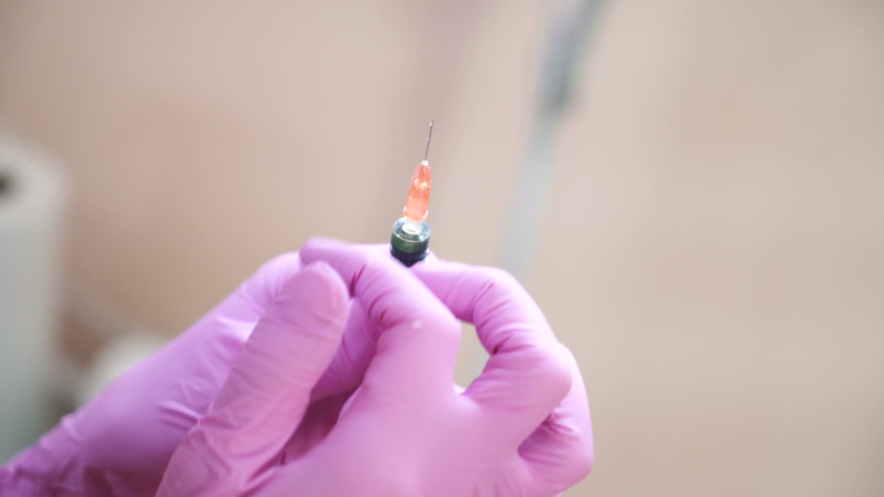 Close up of cosmetician s hand preparing a syringe for injection. Blur. Handheld real time close up shot