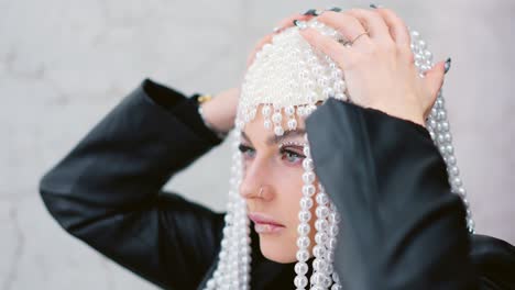 close-up portrait of a woman wearing an elaborate pearl headpiece and artistic eye makeup