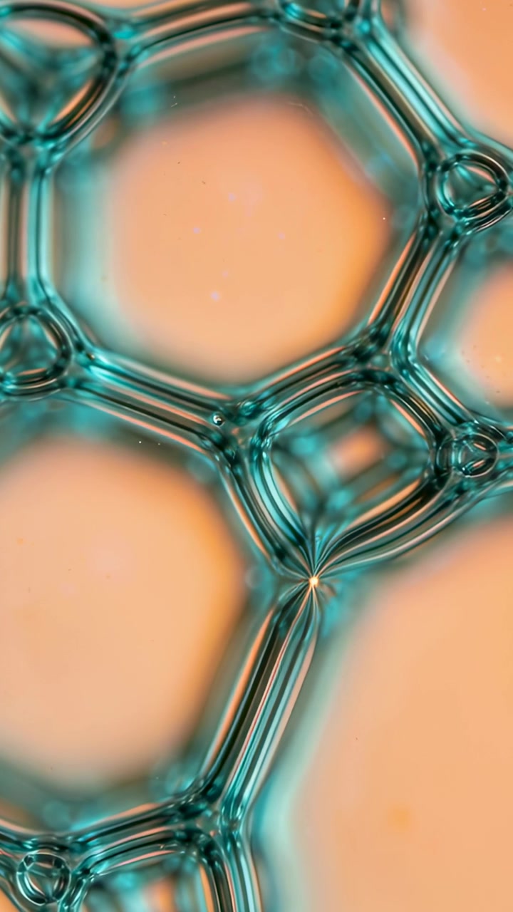 Video verticale: Rete di schiuma in movimento in macro visione, tensione che tira i nodi e assottiglia il collo, bagliore