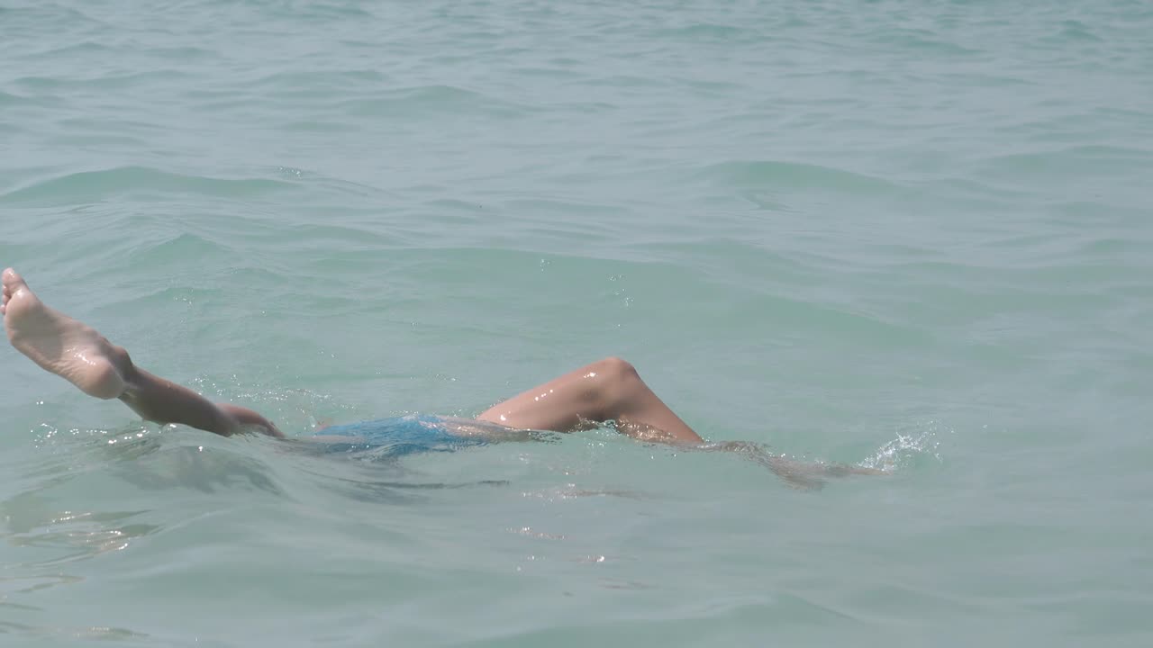 un niño con cabello rubio retiene la respiración y se sumerge en el agua