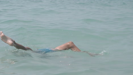 little boy with fair hair holds breath and dives into water