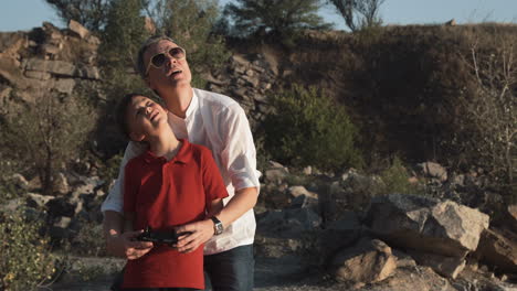 father and son flying a drone in a quarry