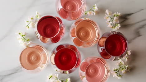 elegant wine glasses with rose and red wine on marble with flowers