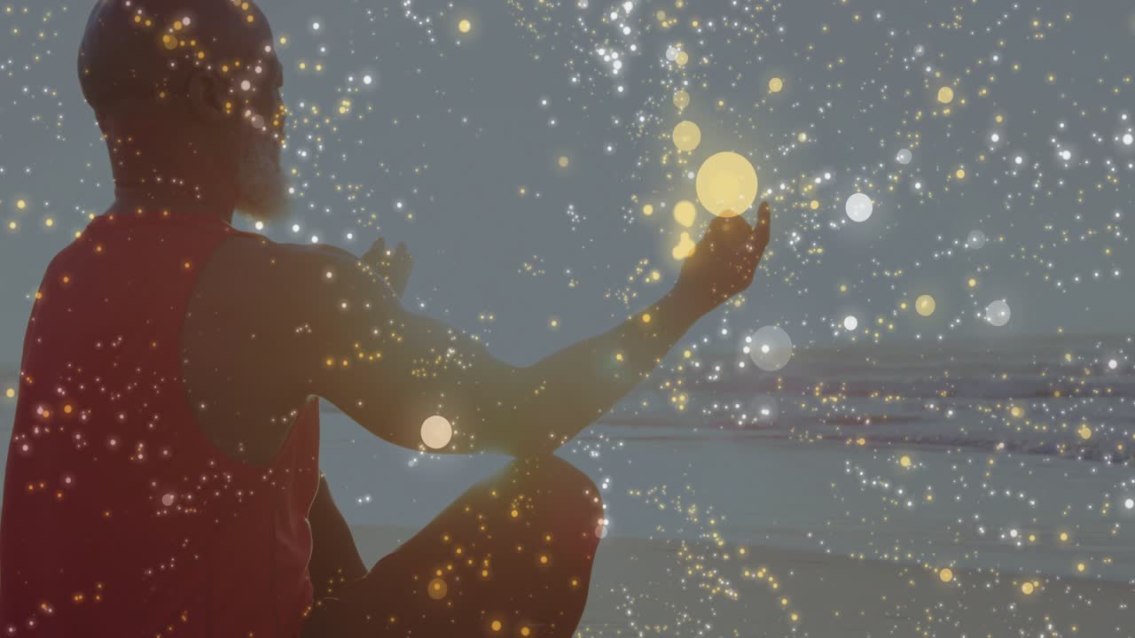 Uomo maturo seduto sulla riva che medita, respira e tende la mano destra verso l'orizzonte mentre un bokeh dorato si sposta.