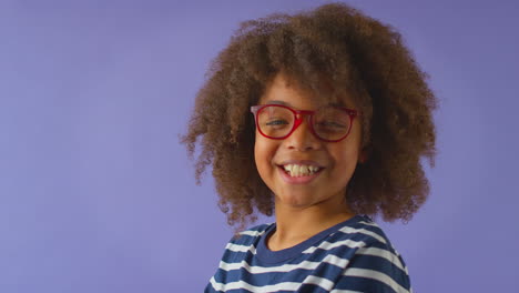 Studio-Shot-Of-Smiling-Boy-Wearing-Red-Glasses-Against-Purple-Background