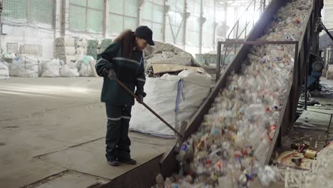 a young african-american woman checks a conveyor belt at a recycling plant. pollution control