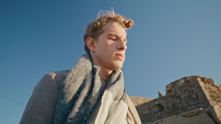 Primo piano di un uomo pensieroso che si gode il sole passeggiando sul lungomare. Ragazzo contemplativo.