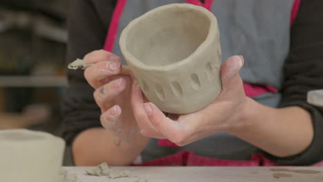 etching unique designs into soft clay with a specialized tool, showcasing artisan's delicate touch