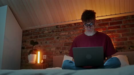 hombre trabajando en la computadora portátil en el dormitorio por la noche
