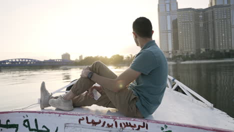 Empuje-Mientras-El-Hombre-Se-Sienta-En-El-Barco-Con-Escritura-árabe-Viendo-El-Amanecer,-Cámara-Lenta