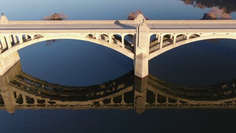 los coches conducen por un puente sobre el agua del río azul oscuro con un hermoso reflejo de sombra durante la hora mágica