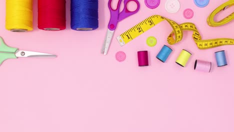 sewing and knitting materials move on top of pastel pink background with copy space. stop motion flat lay