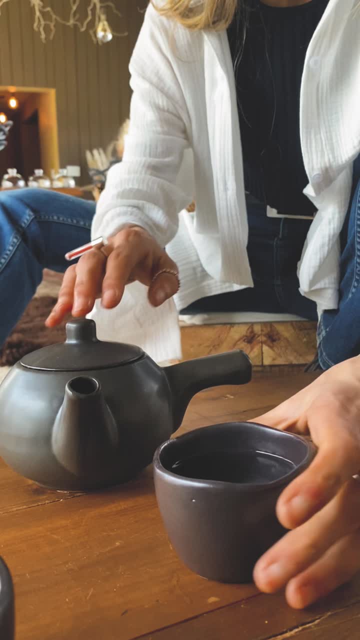 Woman Pouring and Drinking Hot Tea from a Teapot