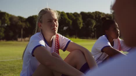 Female-soccer-players-sitting-on-the-ground-on-soccer-field.-4k