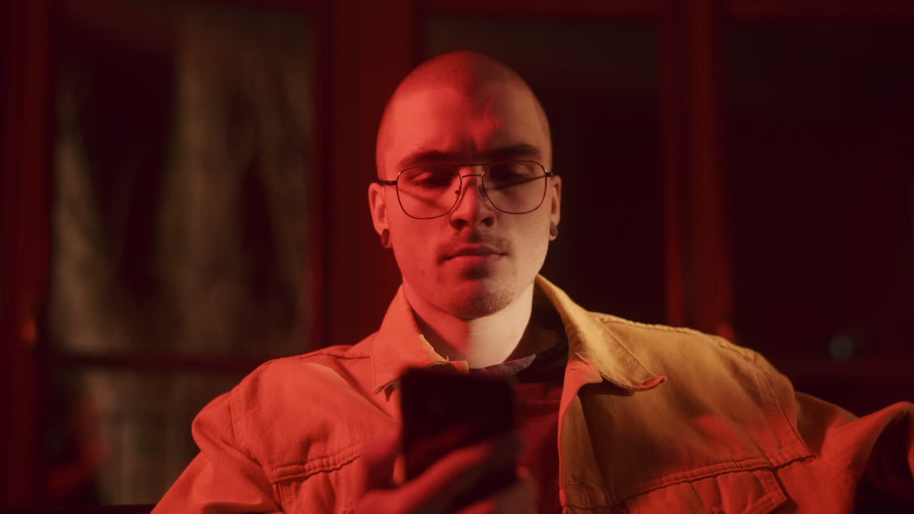 Man using smartphone in dimly lit room with red lighting