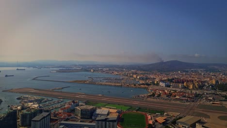 Parallax-aerial-shot-of-boats-and-ships-parked-on-ocean-beside-the-city-during-afternoon