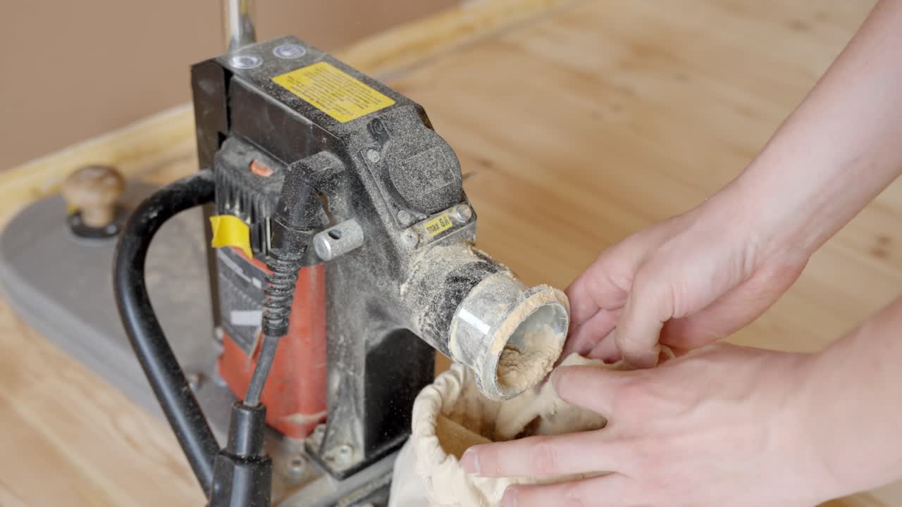 Person Operating Floor Sanding Machine On Wooden Flooring Removing Dust Bag. High Angle Shot