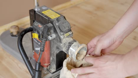 person operating floor sanding machine on wooden flooring removing dust bag. high angle shot